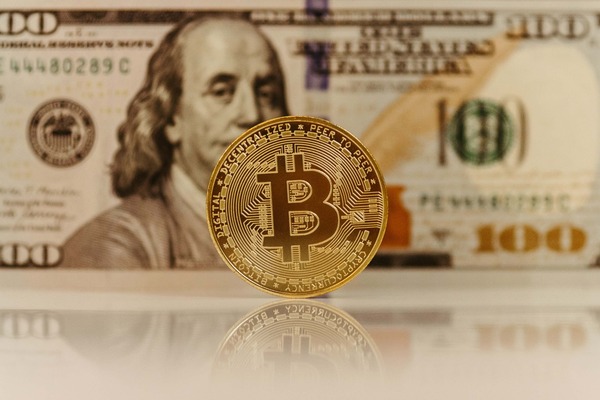 bitcoin on the table in front of a dollar bill